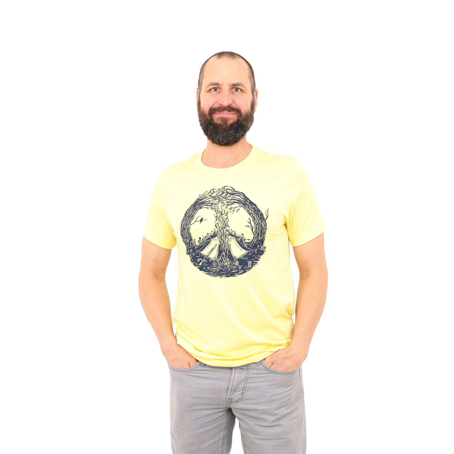 Man wearing yellow t-shirt with print is of a campfire's smoke going up the center meeting with the tops of curved in trees creating a peace sign. Tent is by the fire and a bird is on a branch