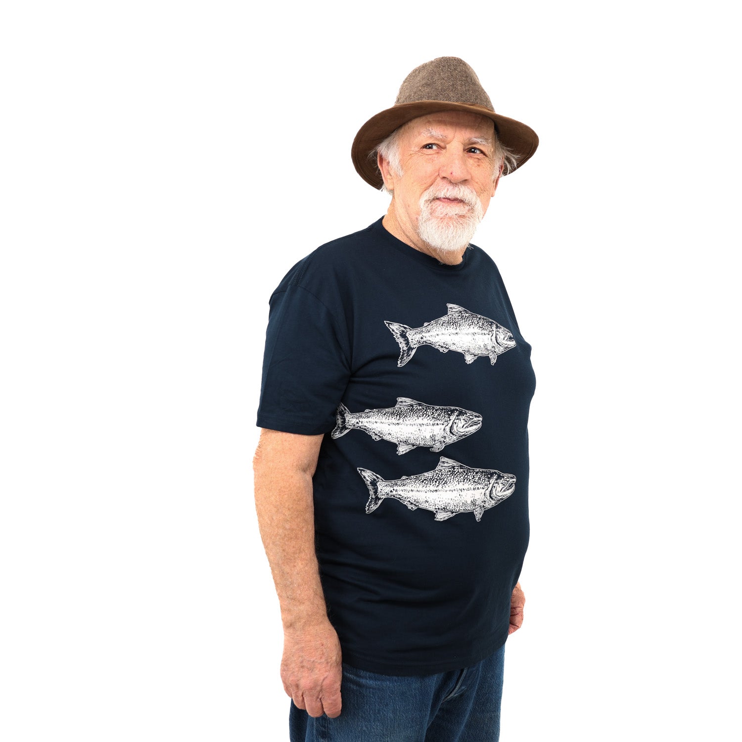 Older man wearing hat smiling to the side with a dark blue T shirt with three white salmon prints