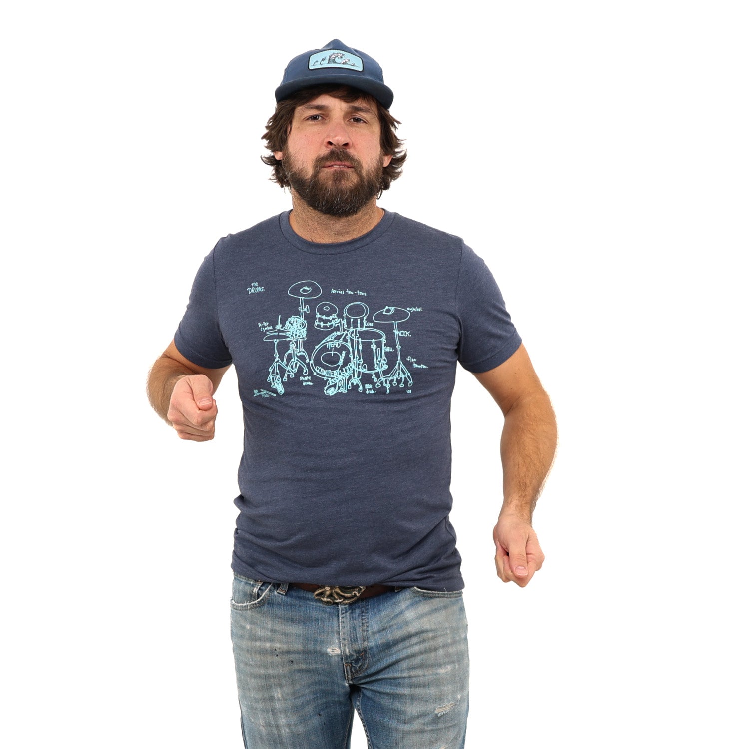 Man pretending to play drums while wearing a ball cap and a blue shirt with a drum set screen printed on it. White background.