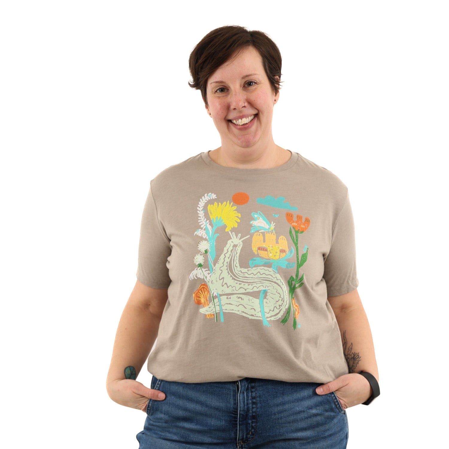 Woman wearing light brown t shirt with colorful print of plants and bugs