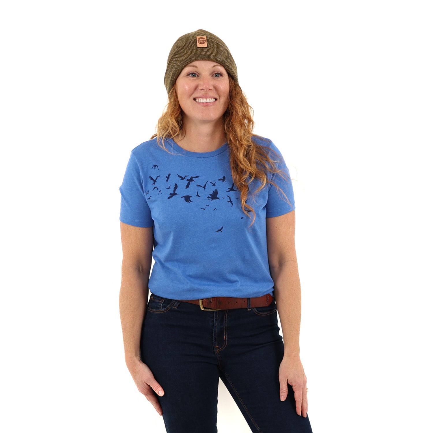 woman wearing green/brown beanie with blue t-shirt with dark blue ink of birds flying.