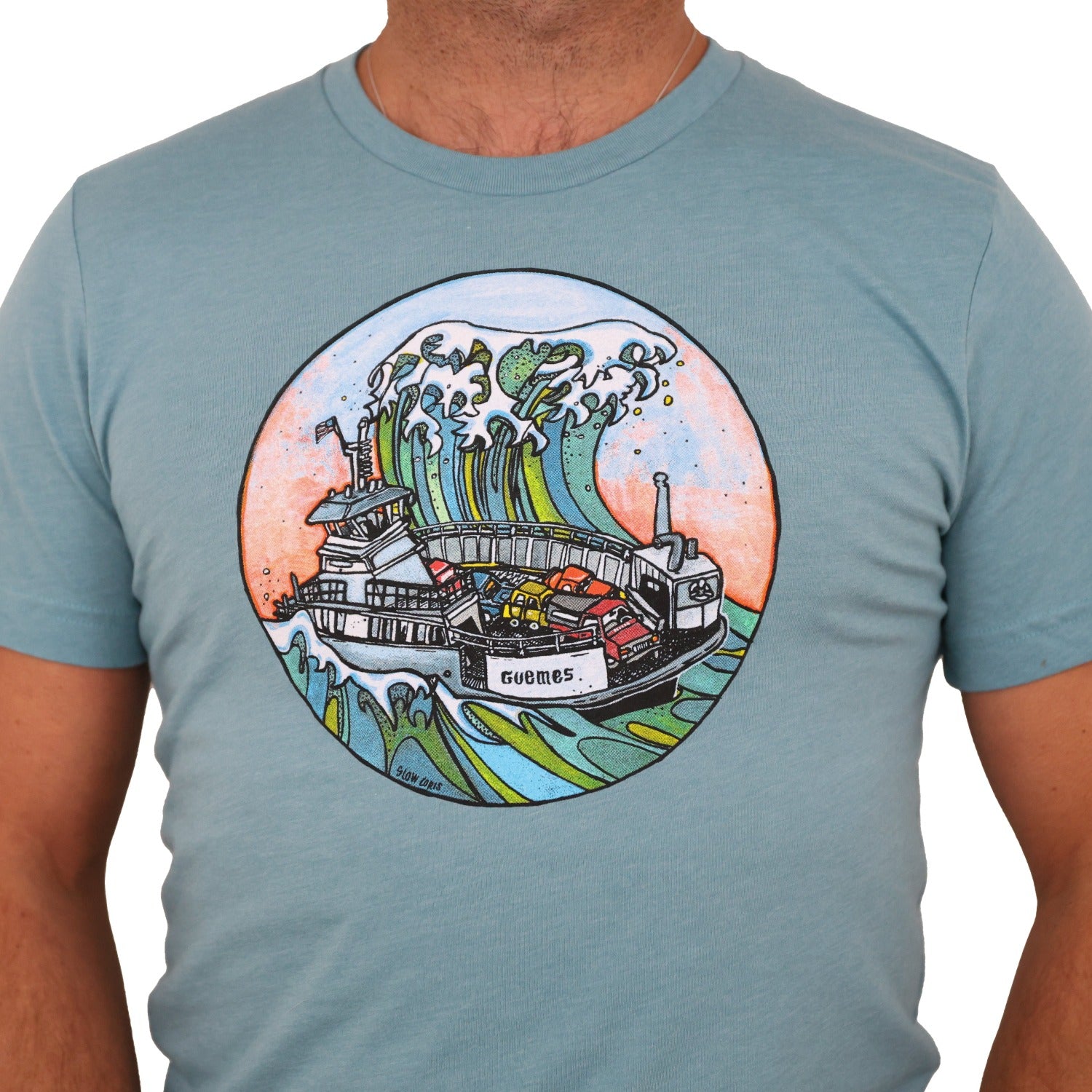 man wearing a light blue t-shirt with a screen print of a huge wave about to engulf the Guemes ferry