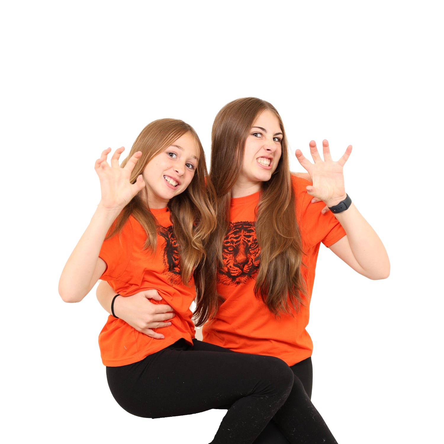 Two girls making roar faces with claws while wearing a Slow Loris orange tiger printed shirt