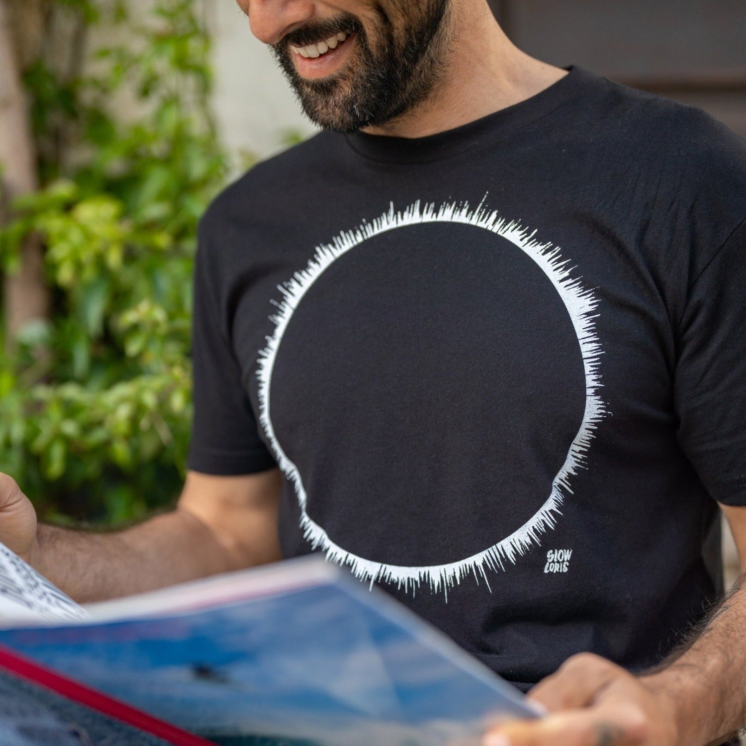 Close up of man reading a menu while wearing a black t-shirt with a white eclipse print on it.