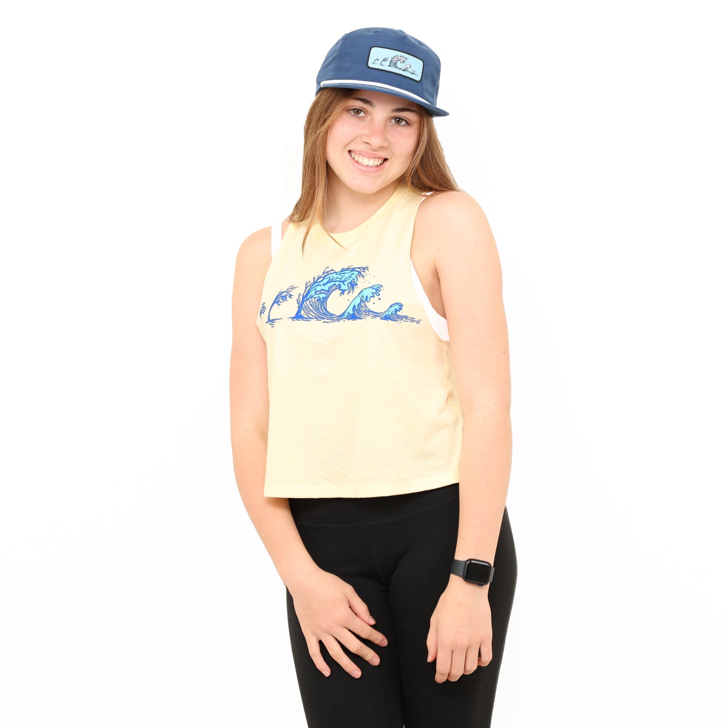 girl wearing soft yellow tank with blue tree wave design on it in a white background