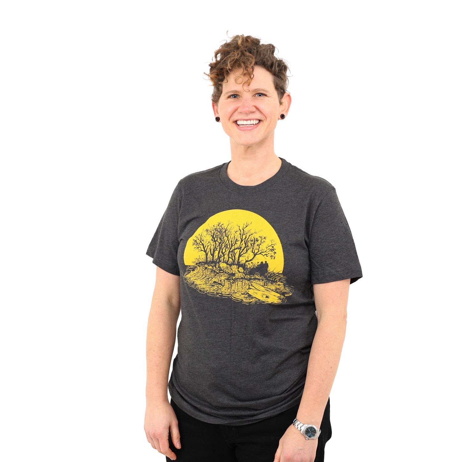 nice smiling woman wearing a grey t-shirt with yellow print of kayakers on a sunset island.