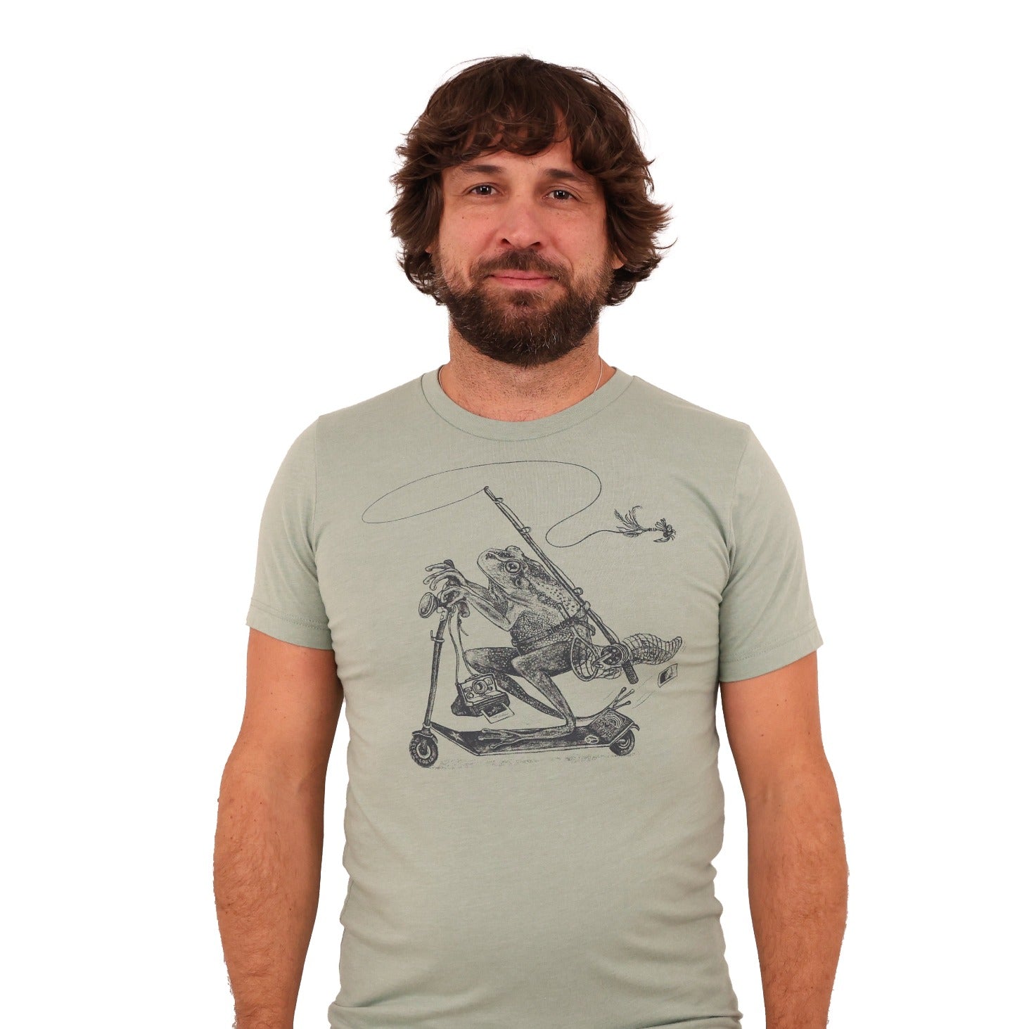 Man wearing green shirt with print of a frog riding a scooter with a fly fishing rod, net, polaroid camera