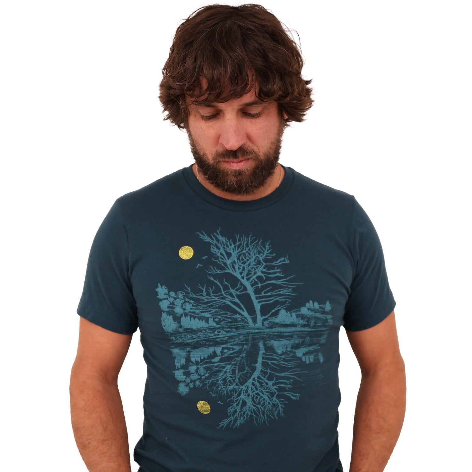 Man wearing atlantic blue t-shirt. Print is in a light blue tree & reflection over water with a yellow moon.