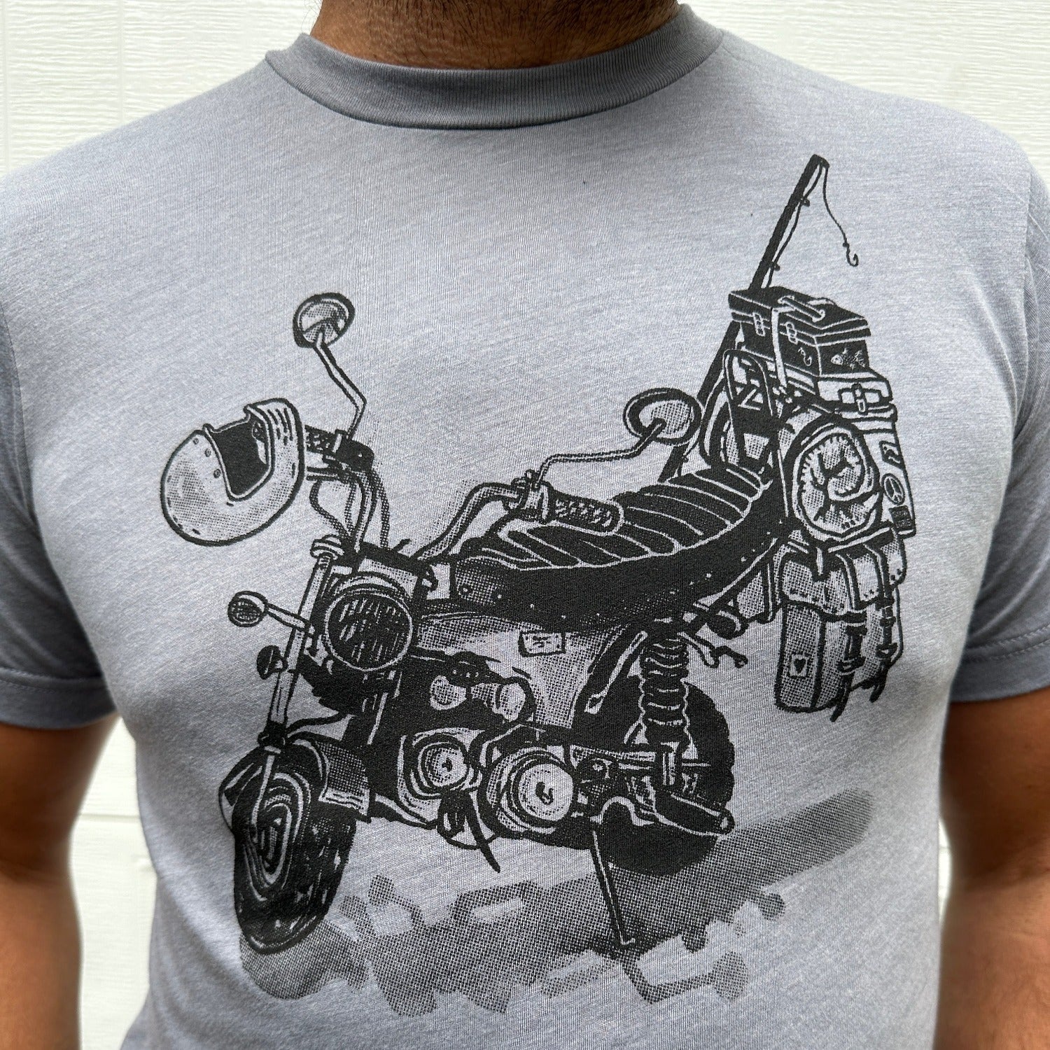 Black print on a grey colored t-shirt. Print is of a mini-bike loaded up with fishing pole, helmet, sleeping bag, and bags.