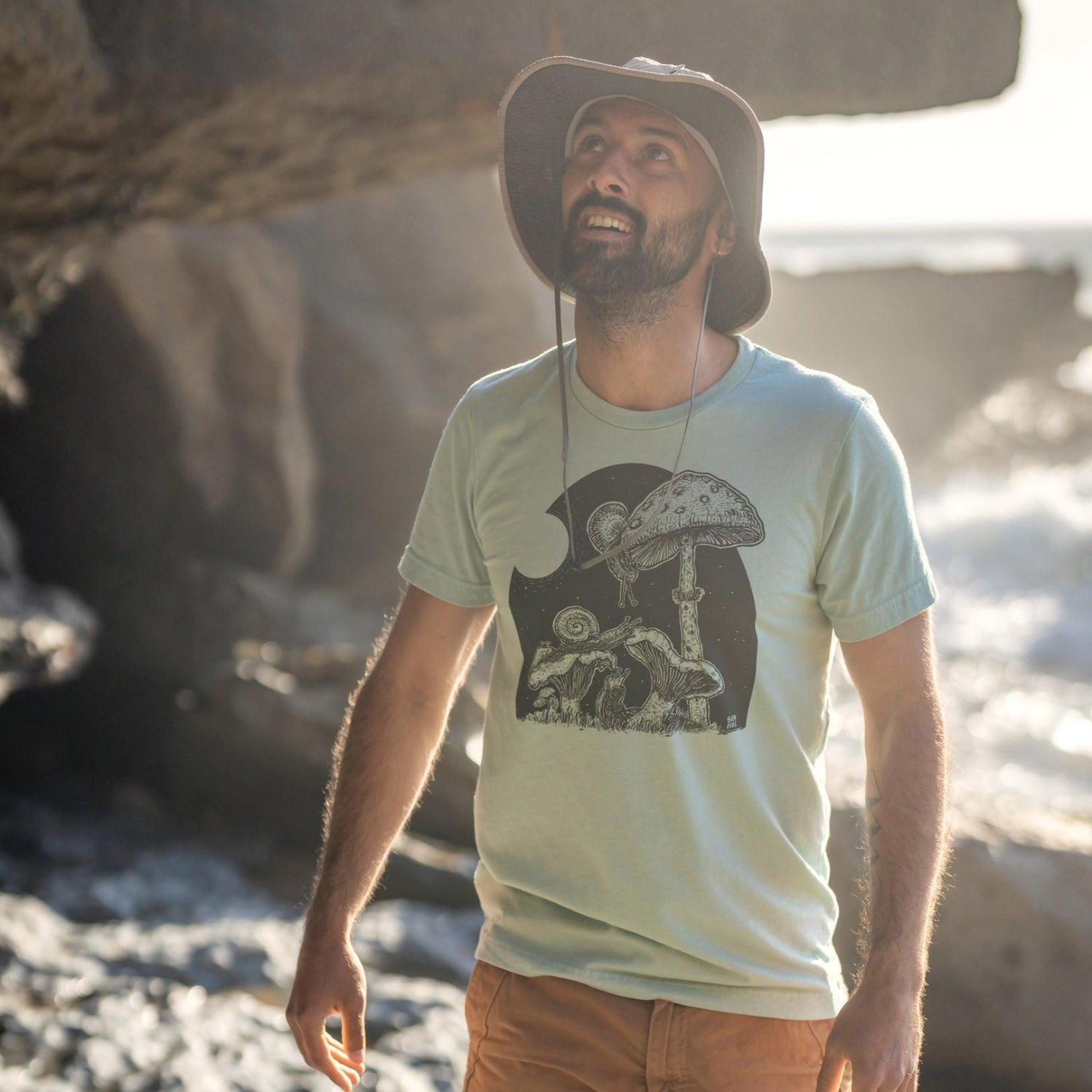 man on beach wearing a mint shirt with snails eating mushrooms in the full moon light.