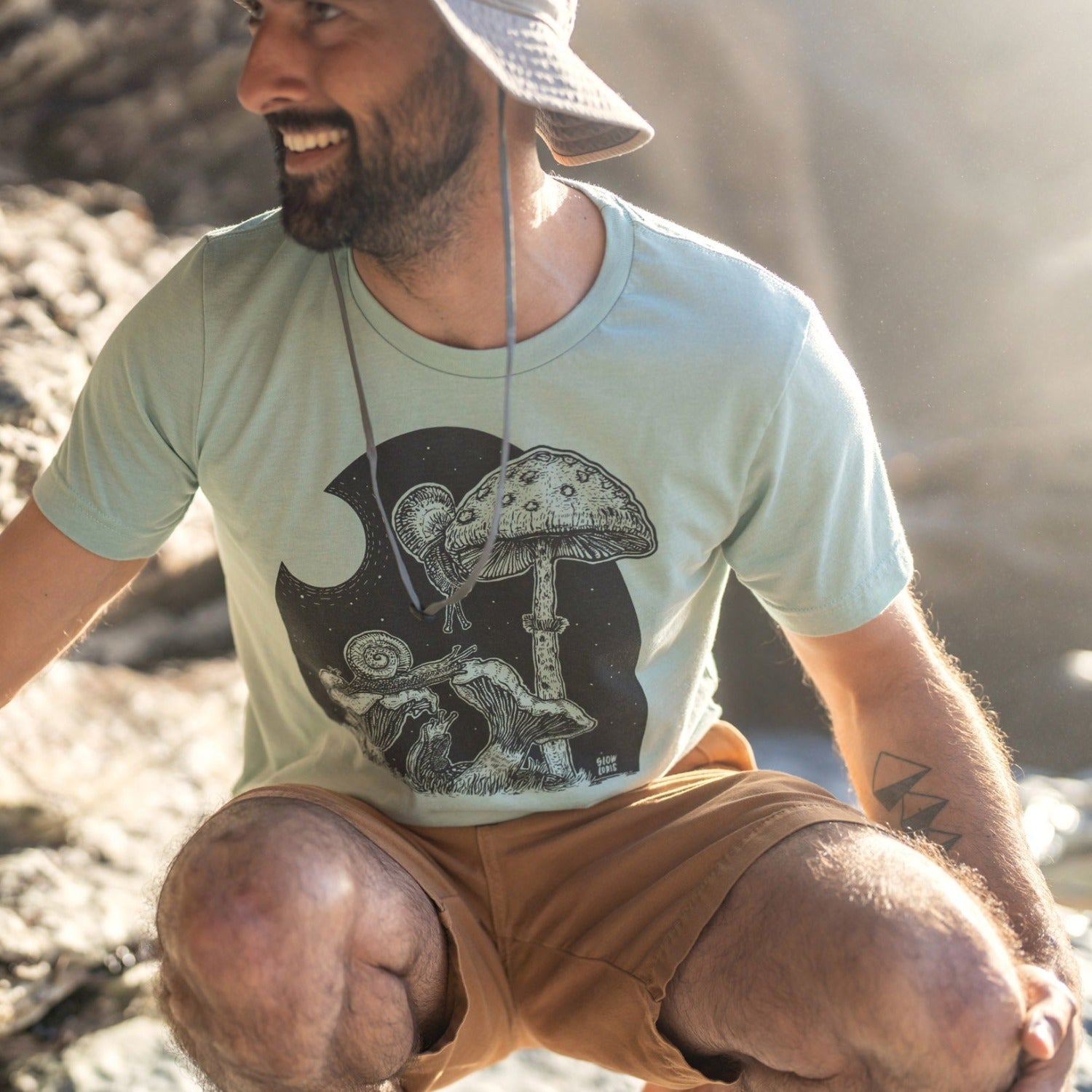 man on beach wearing a light green shirt with snails under a full moon eating mushrooms .