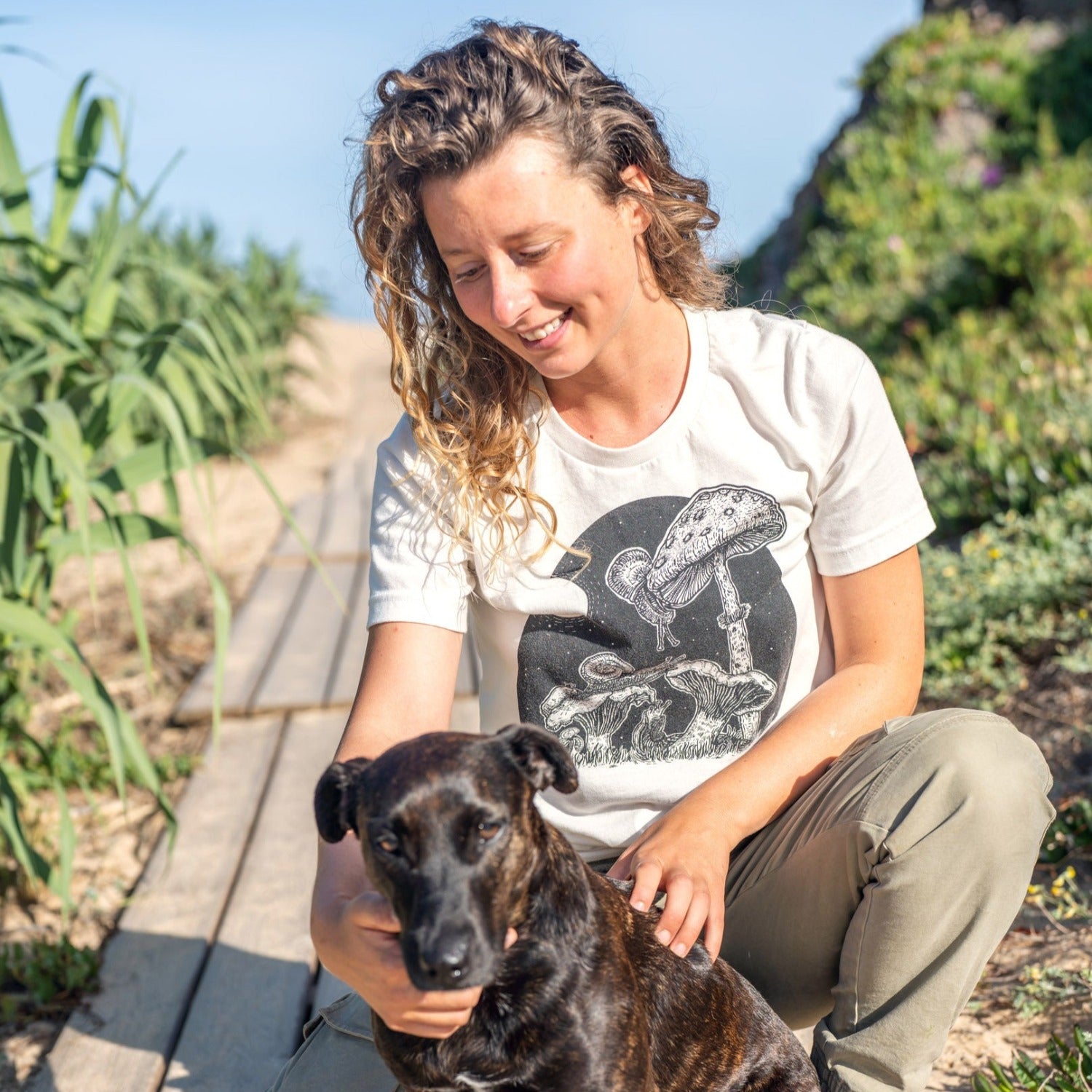 Girl petting dog while wearing a white shirt with snails eating mushrooms in the full moon light.