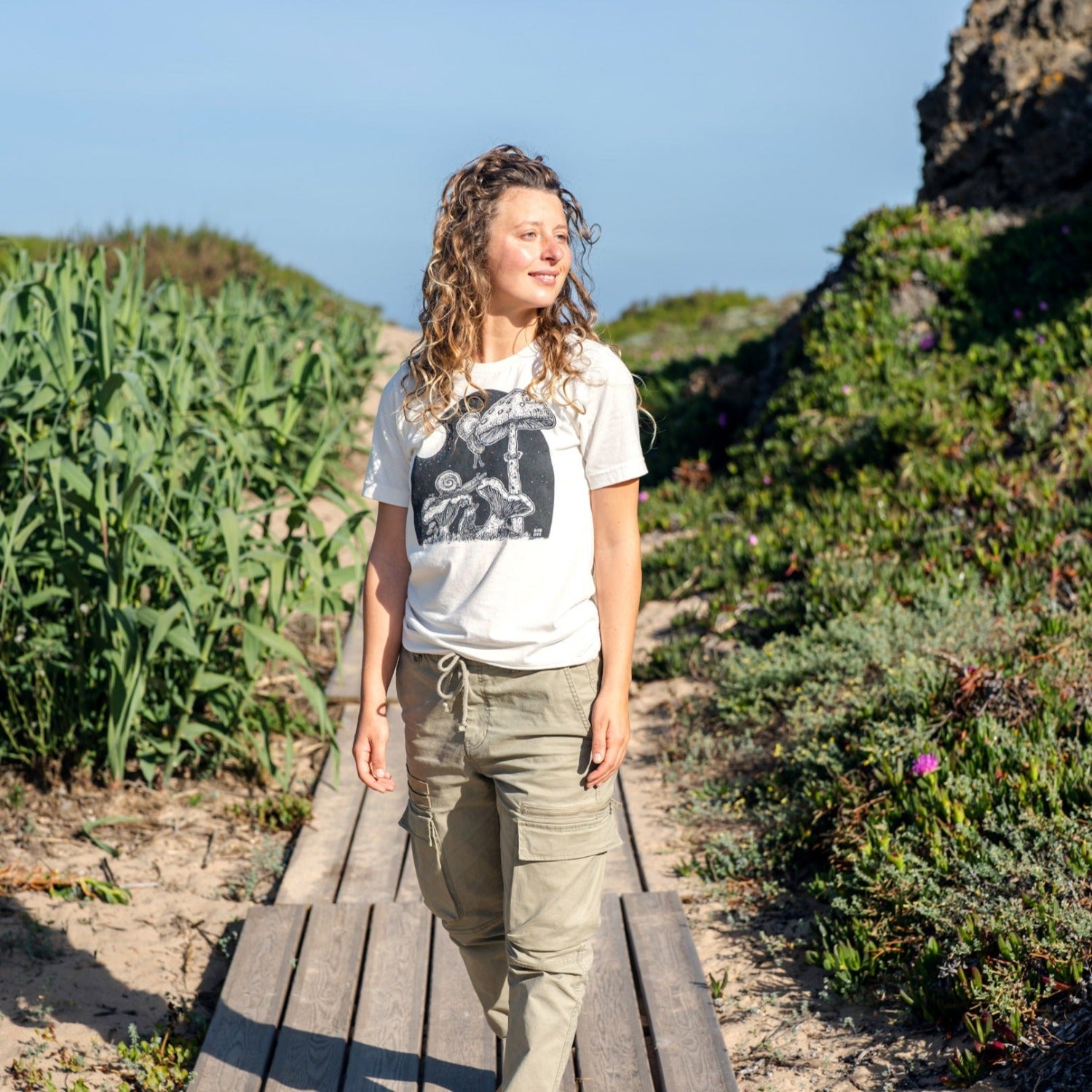 Girl on boardwalk wearing a white shirt with snails eating mushrooms in the full moon light.