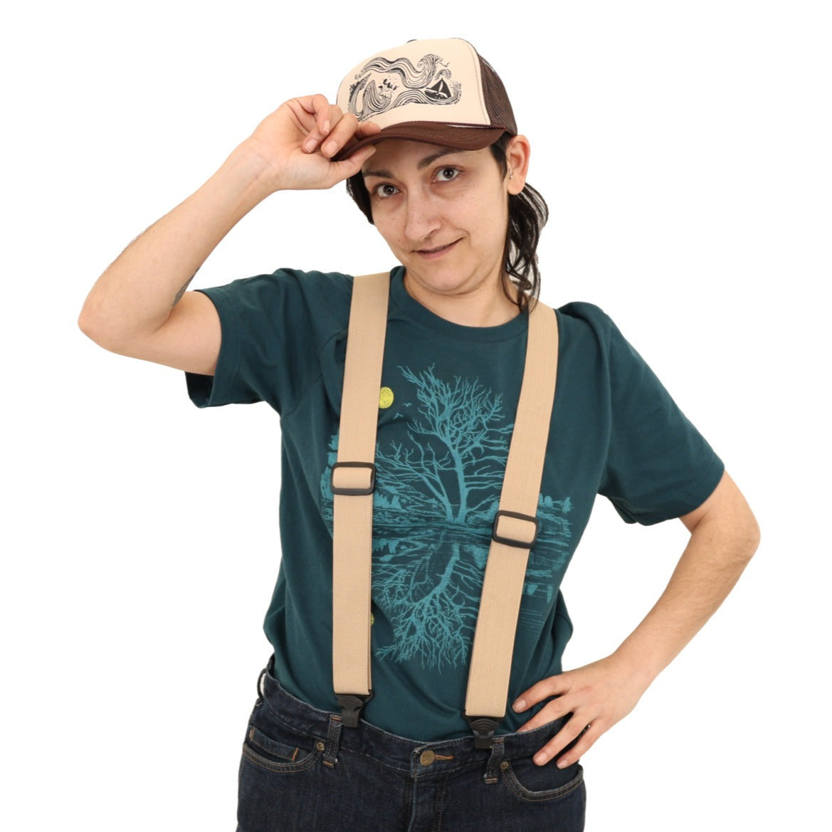 woman wearing suspenders over a green t-shirt with light blue ink and a yellow moon with scene reflecting over water.