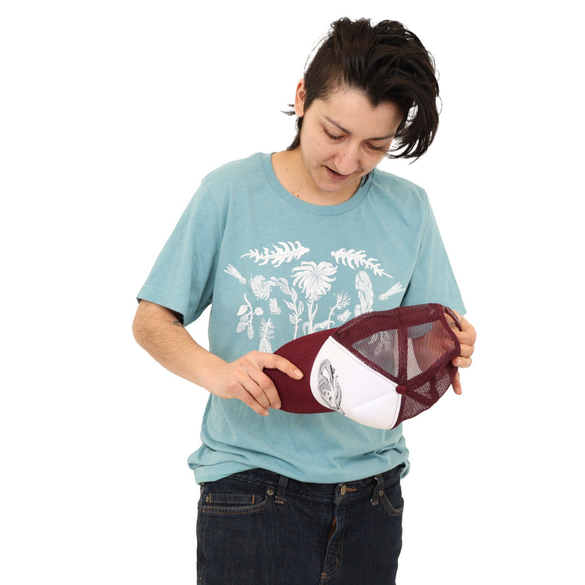 Woman wearing a light blue colored t-shirt with white ink of flowers, ferns, feathers, shells, etc