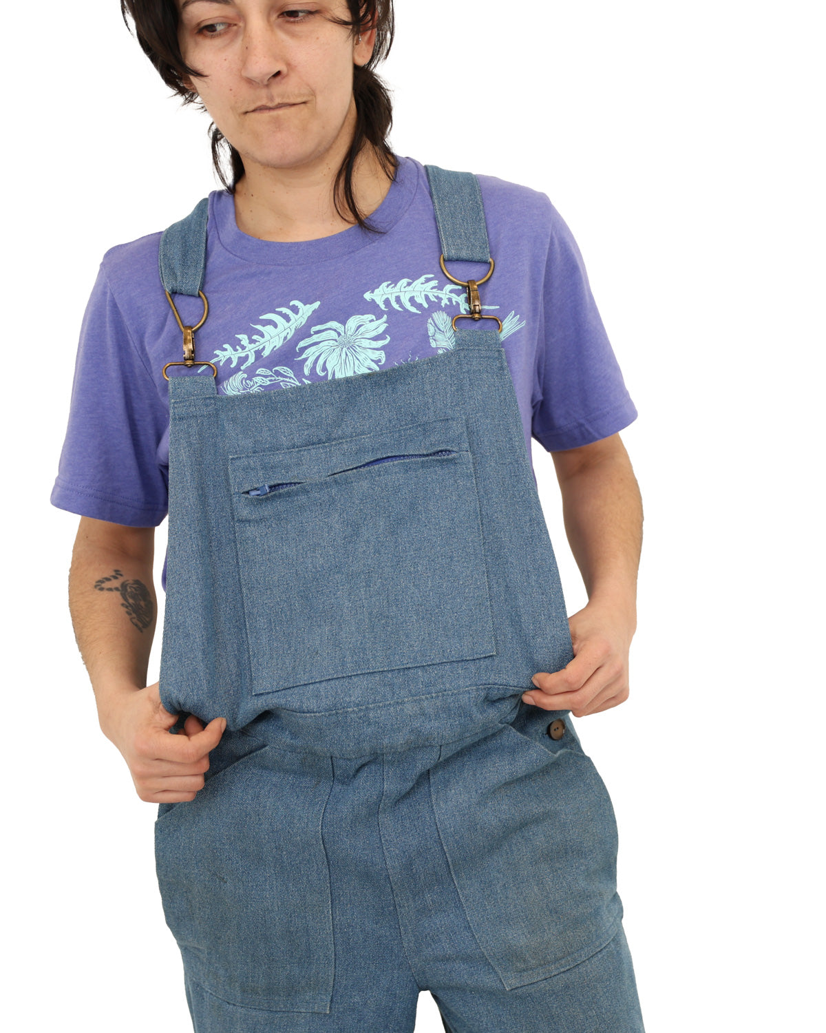Woman wearing a light purple colored t-shirt with light blue ink of flowers, ferns, feathers, shells, etc