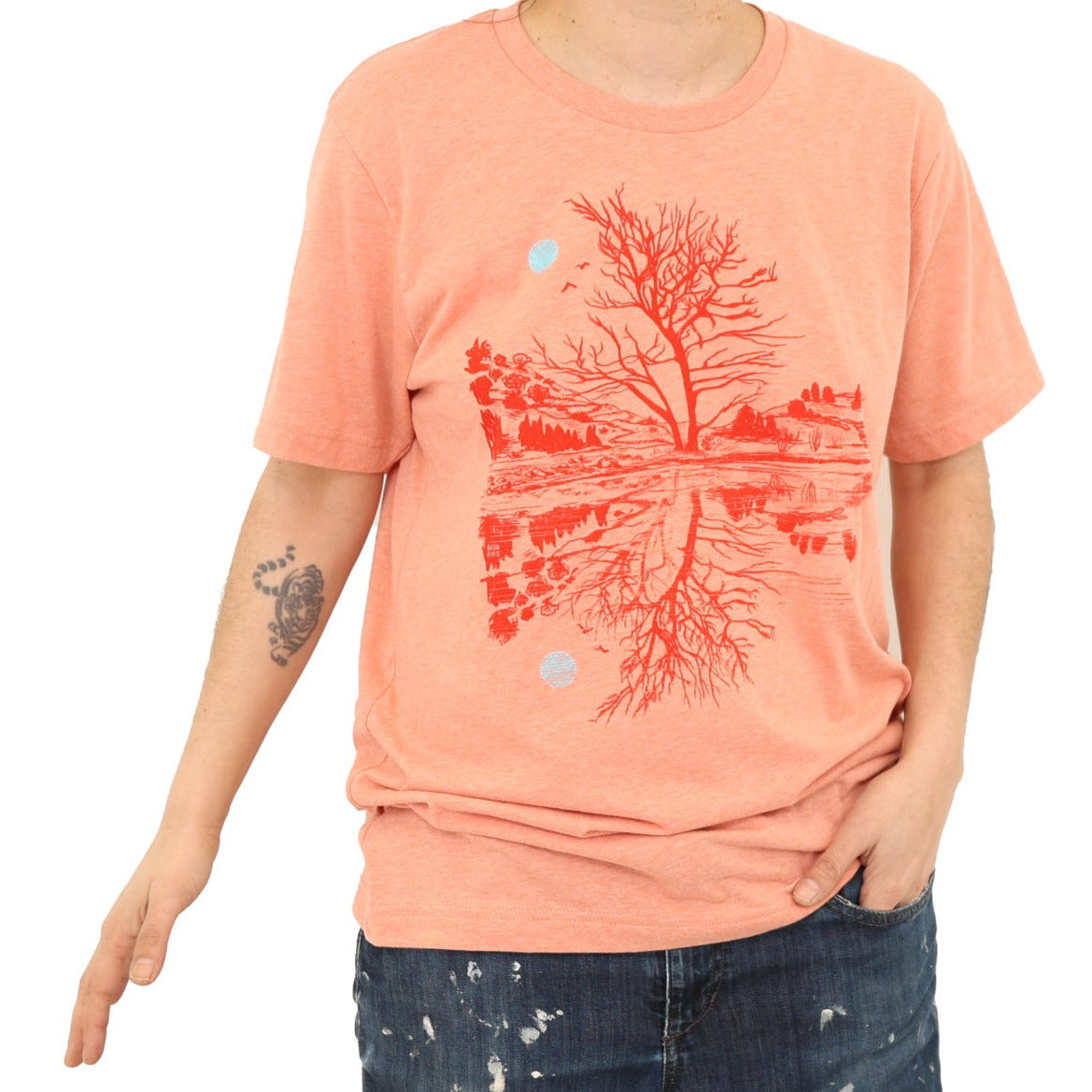 woman wearing sunset orange t-shirt with darker orange print of moon and scene reflection over water.