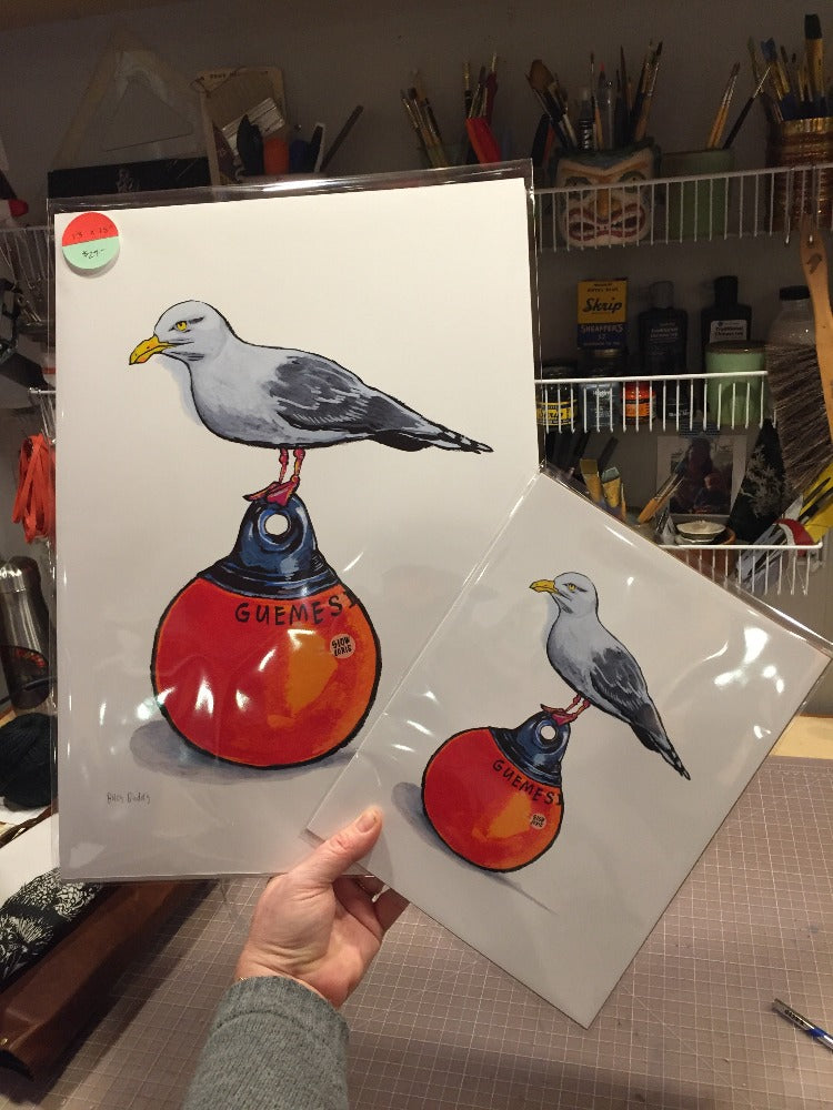Art prints of a seagull on a buoy. One large, one smaller, held next to each other.