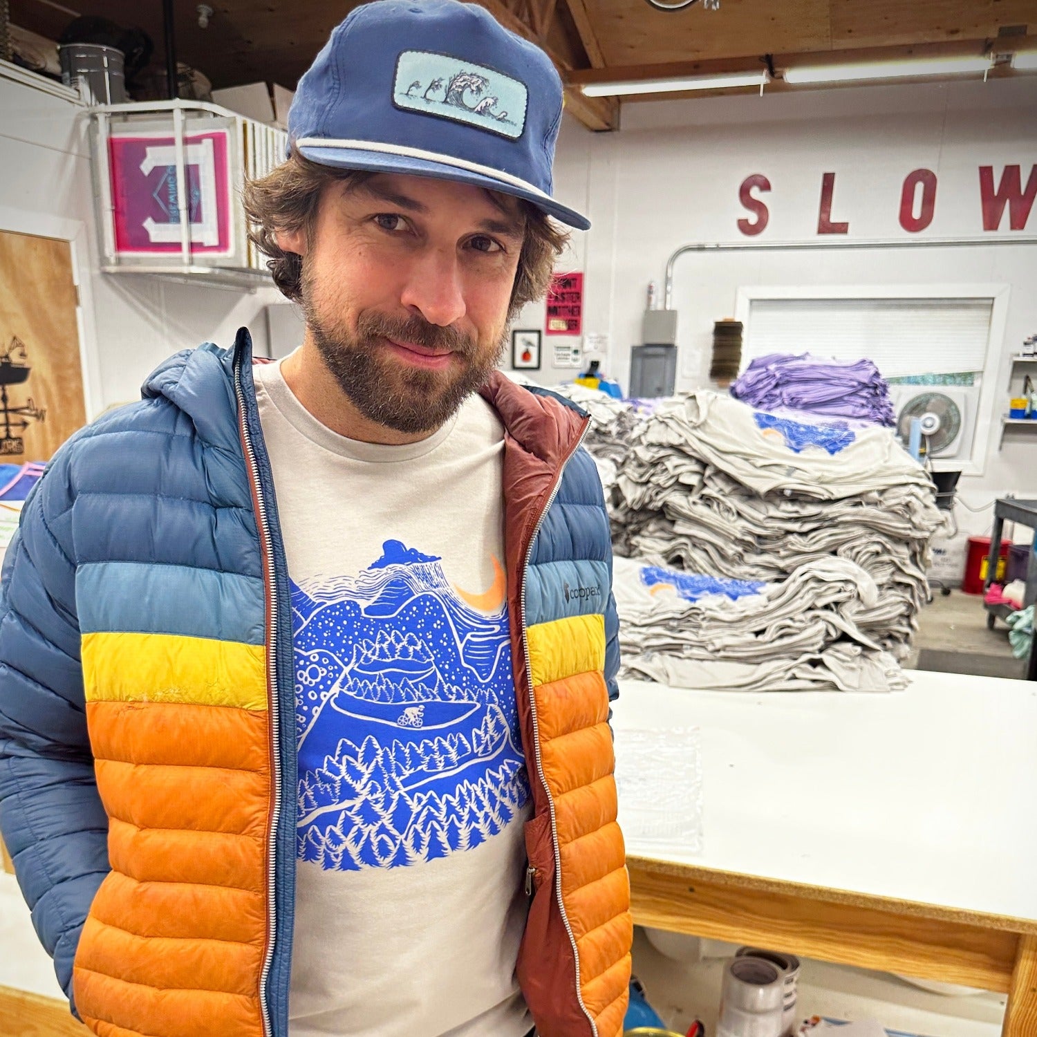 Night Ride print on tan shirt in dark blue ink. Mountain scene with raincloud, crescent moon, and bicyclist riding down the mountain