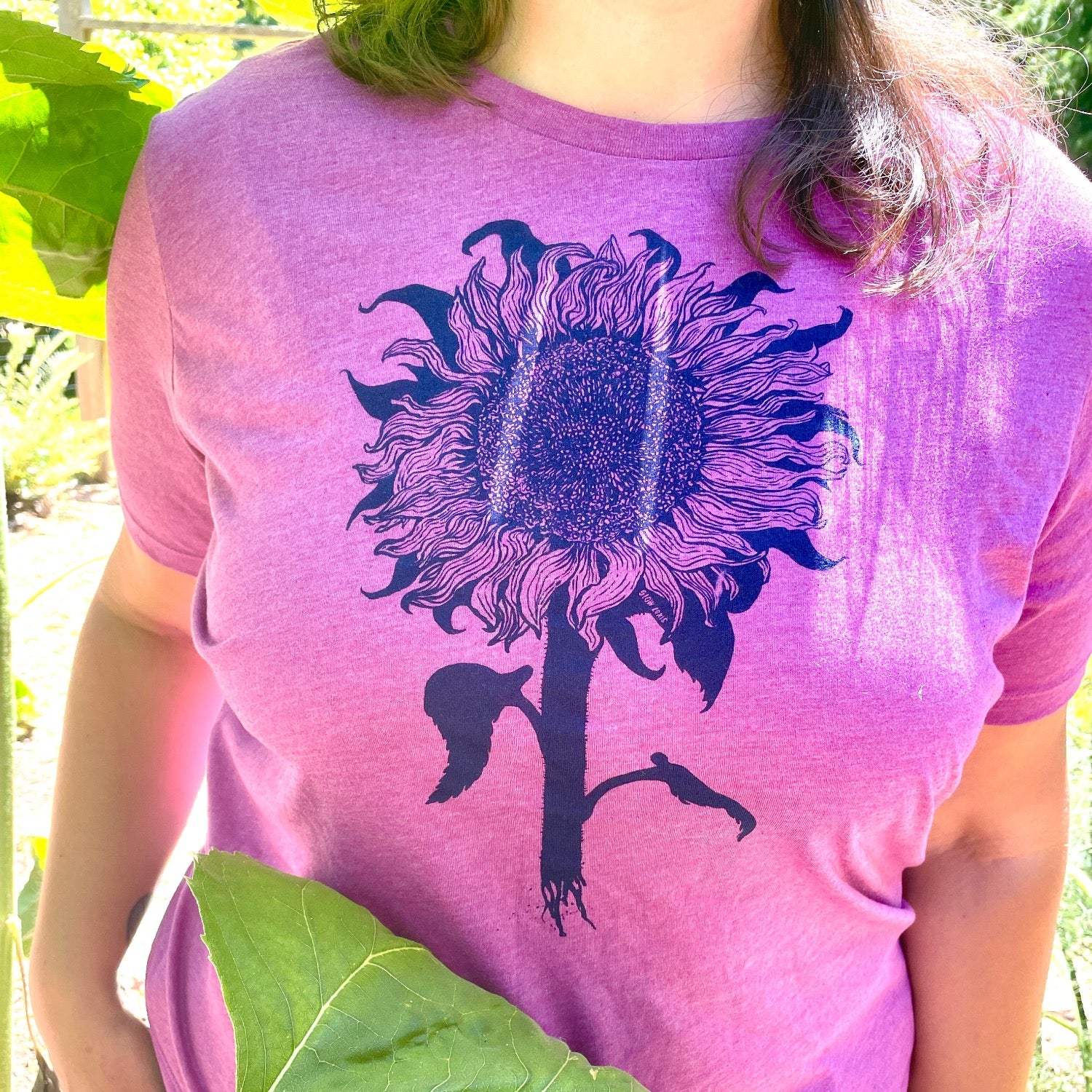 Woman wearing purple tinted pink shirt with a sunflower printed in