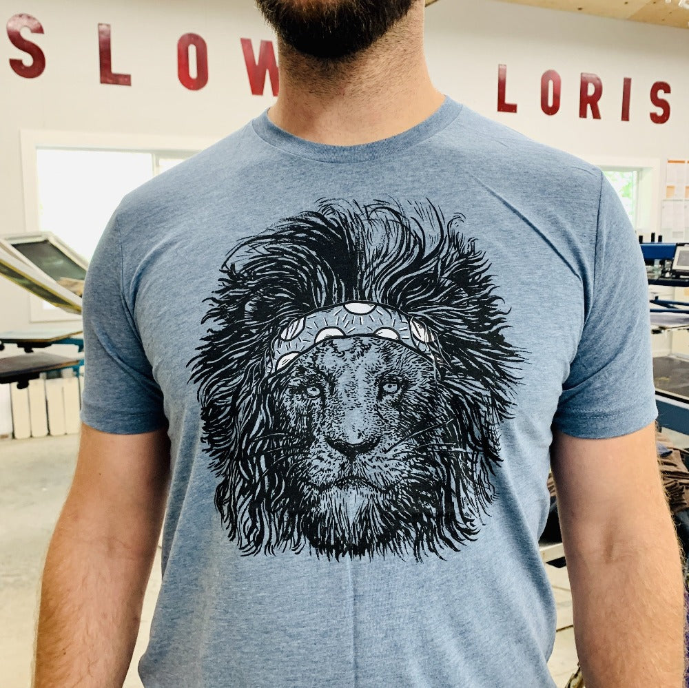 Cliff in the shop wearing a steel blue tee with a screen printed lion wearing a headband on it.