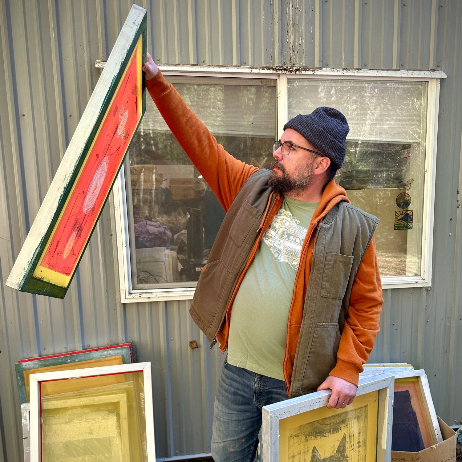 Man holding up a screen while wearing a light green shirt with a loaded up RV on it.