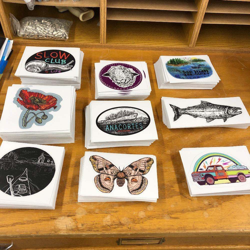 A variety of stickers laid out on a desktop, including our Dream Truck sticker.