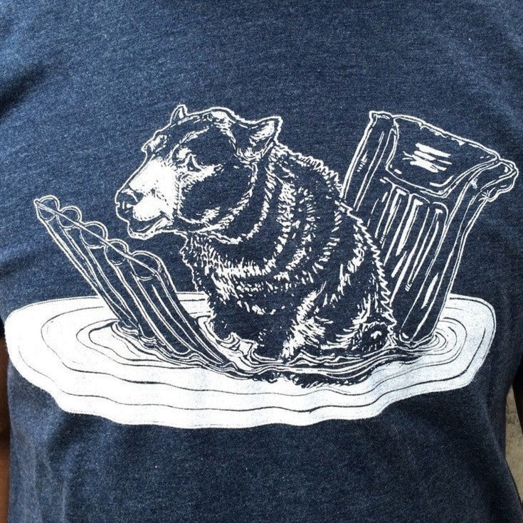 Close-up of blue t shirt with white print of a bear on a pool floatie.