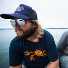 Man in a boat on the water, wearing a t shirt printed with a Dungeness crab.