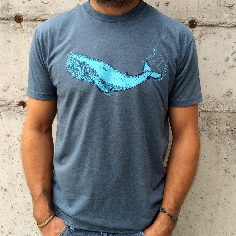 Blue t shirt printed with a whale in two colors, modeled by man in jeans.