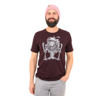 Man wearing maroon t shirt with white print of close up of tree man holding skis with ski poles in his top branches