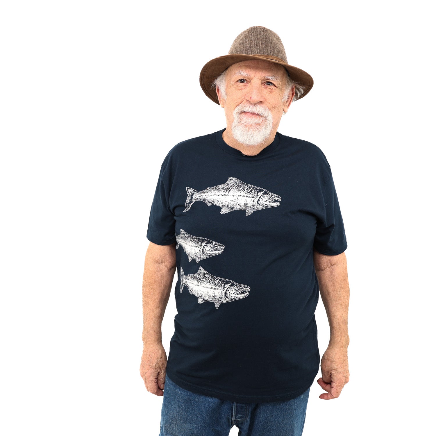 Older man wearing hat smiling to the side with a dark blue T shirt with three white salmon prints