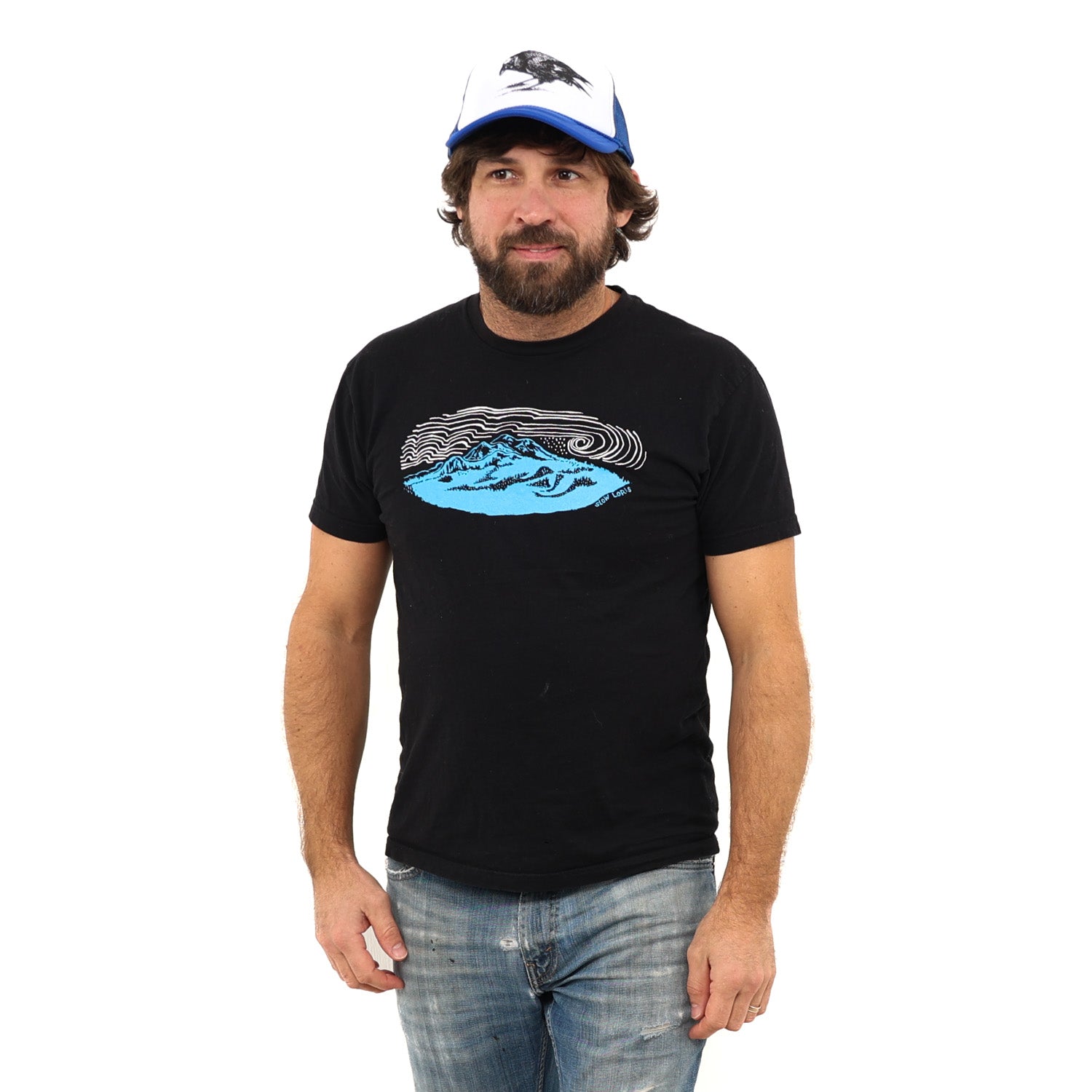Man wearing a ball cap in blue jeans and a black t-shirt with a blue mountain and white wind lines screenprinted