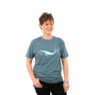 Woman with super cool short curly hear wearing a blue/grey t-shirt with a blue whale on it. 
