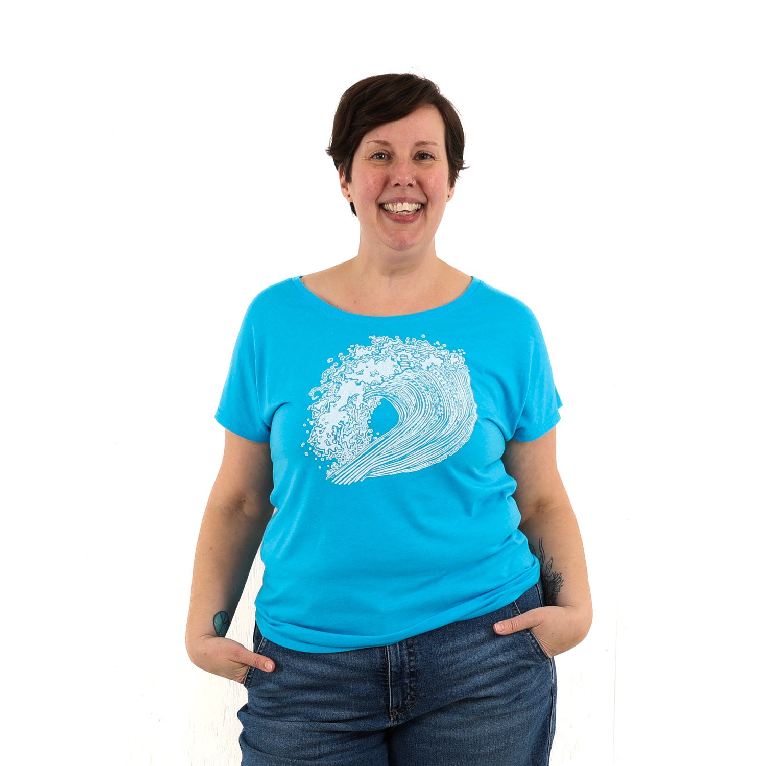 Woman wearing bright blue t shirt with a big wave printed on it in white ink