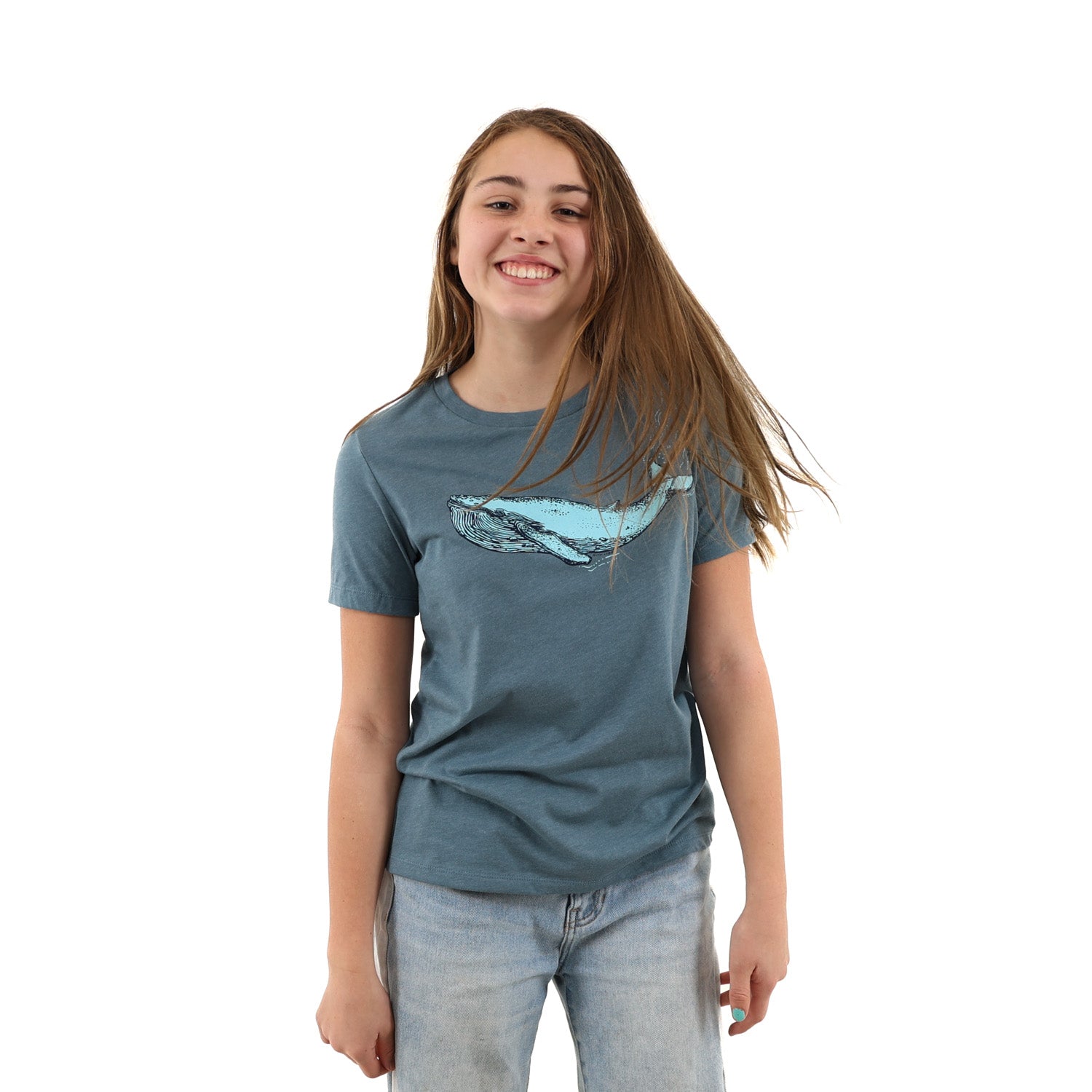 Girl standing with hands in her jean pockets while wearing a blue t shirt with a blue whale screen printed across the chest/boob zone.