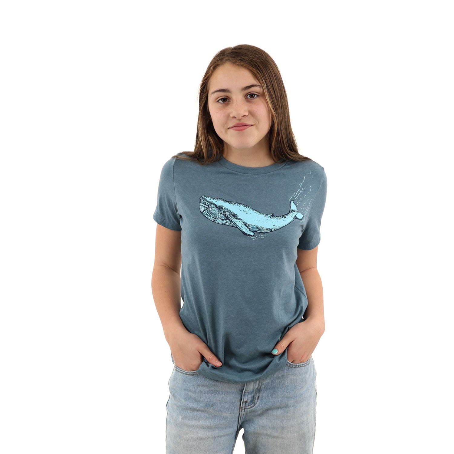 Girl standing with hands in her jean pockets while wearing a blue t shirt with a blue whale screen printed across the chest/boob zone. 