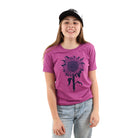 Young girl wearing purple tinted pink shirt with a sunflower printed in 