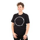 woman with white background wearing a black t-shirt with white eclipse print on it. 