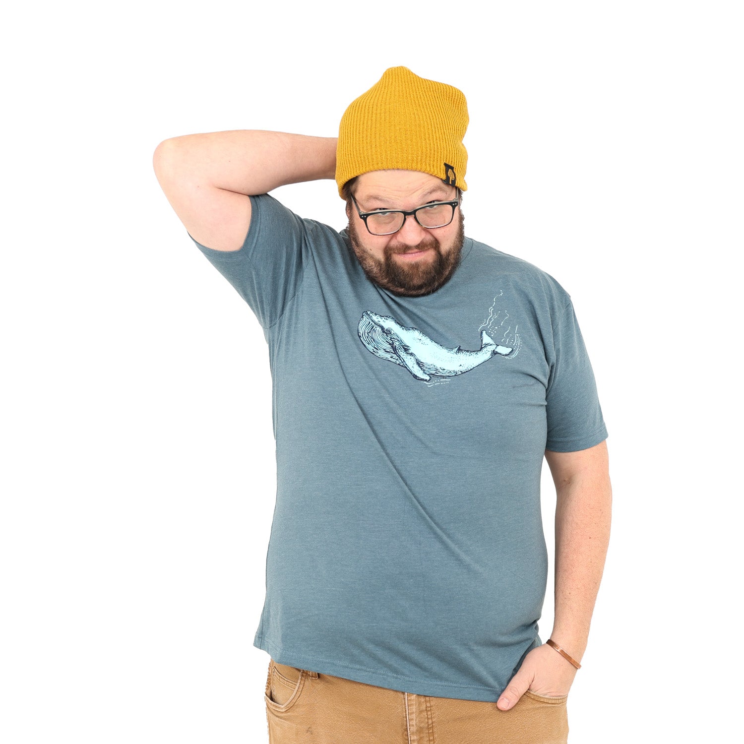 Man wearing glasses, a mustard benie and a blue/grey shirt that has a blue whale screen printed on it. 