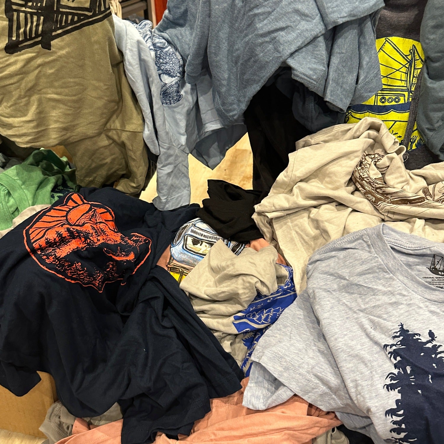 pile of different colored t-shirts with different designs and colors of inks.