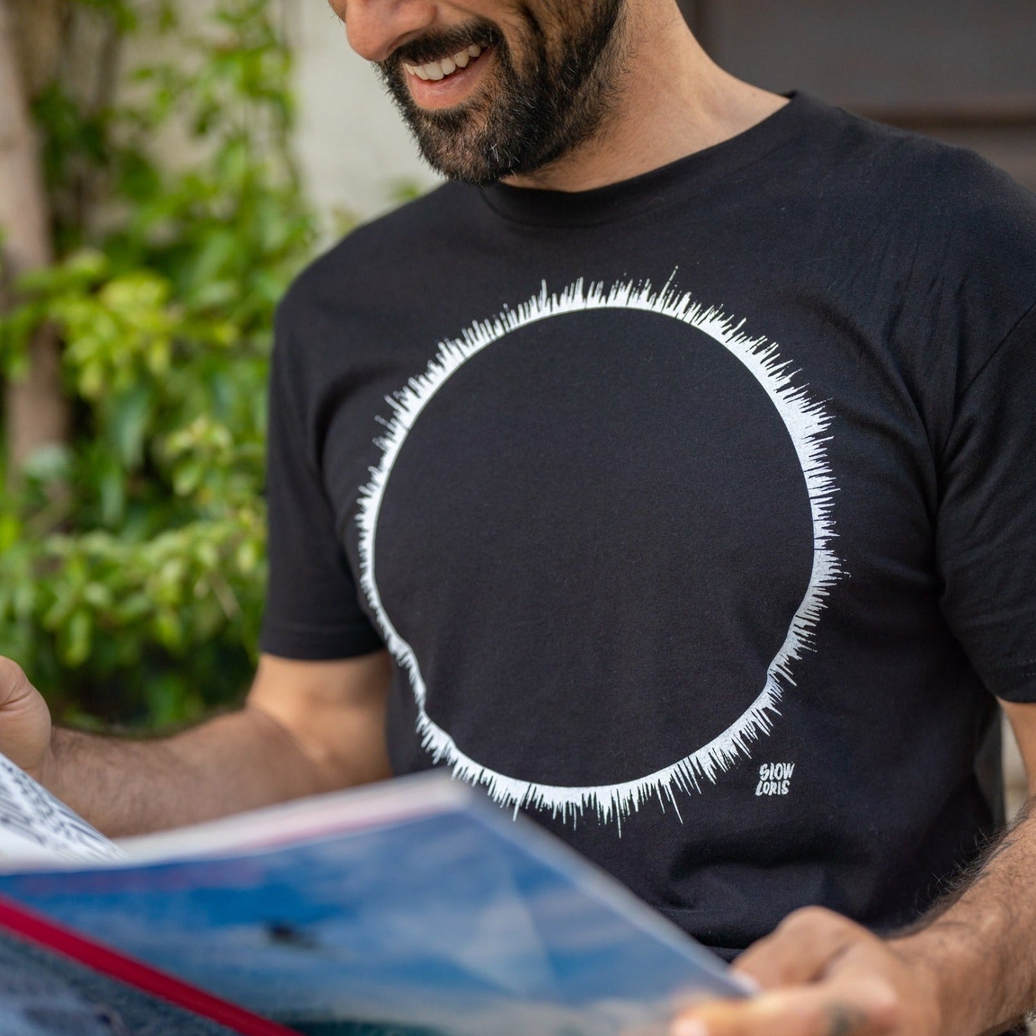 Close up of man reading a menu while wearing a black t-shirt with a white eclipse print on it. 