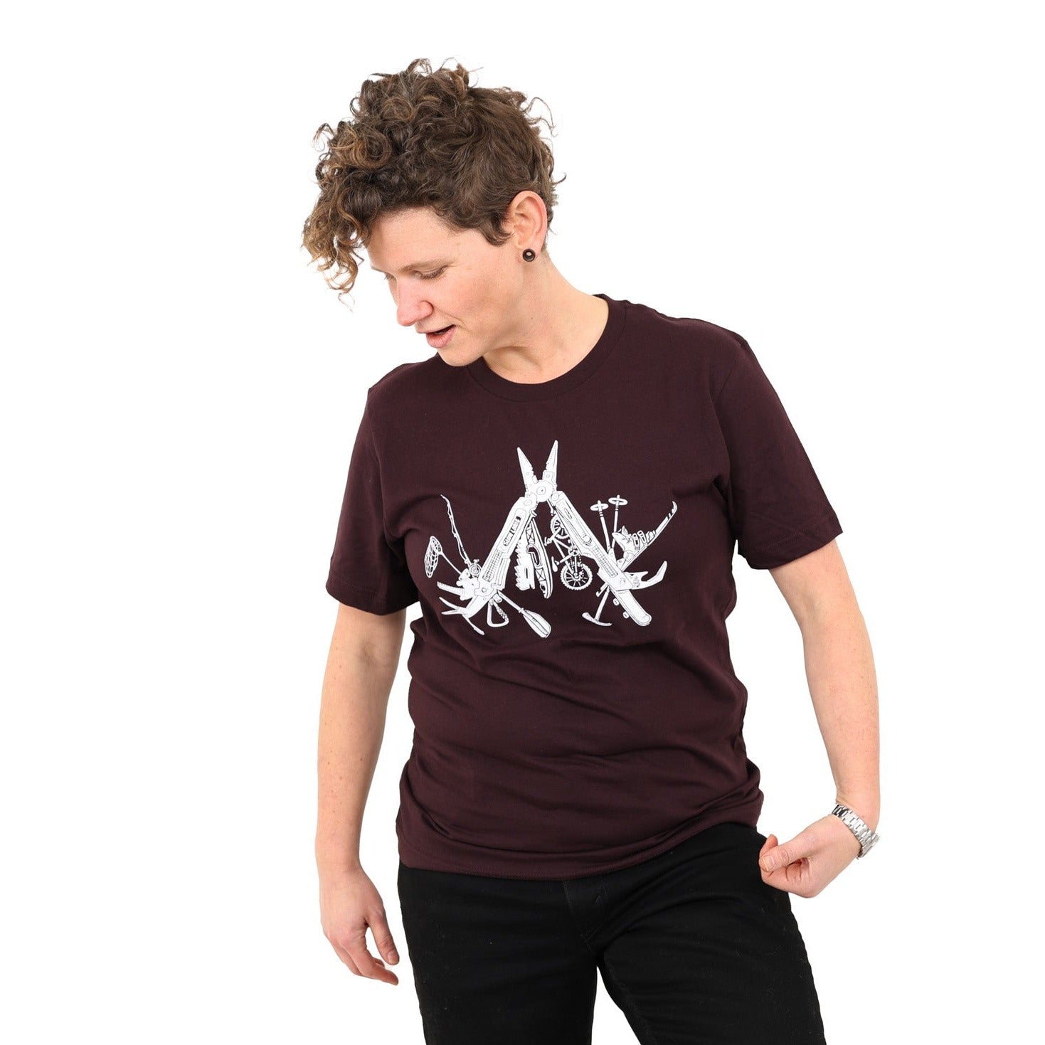 Woman wearing oxblood colored t-shirt with a white print of a multitool. The tools within the multitool are actually adventuring items- kayak, fishing pole, skis, ice axe, etc etc.