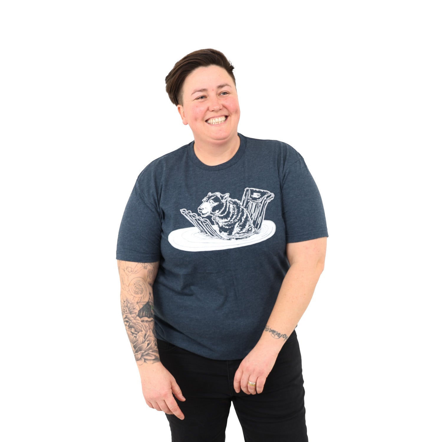 Woman with short dark hair wearing a blue t shirt screen printed with a bear sitting on a floatie in the water.