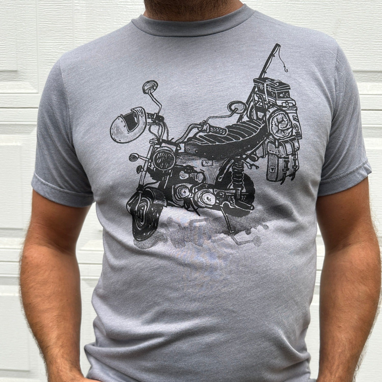 Black print on a grey colored t-shirt. Print is of a mini-bike loaded up with fishing pole, helmet, sleeping bag, and bags.