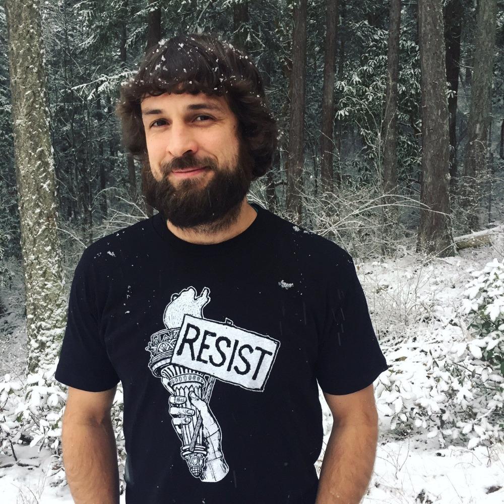 man in the snow wearing a black t-shirt that has a liberty torch with a resist sign 