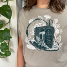Woman wearing light brown t shirt of a Walkman printed in green with plants growing around it printed in white