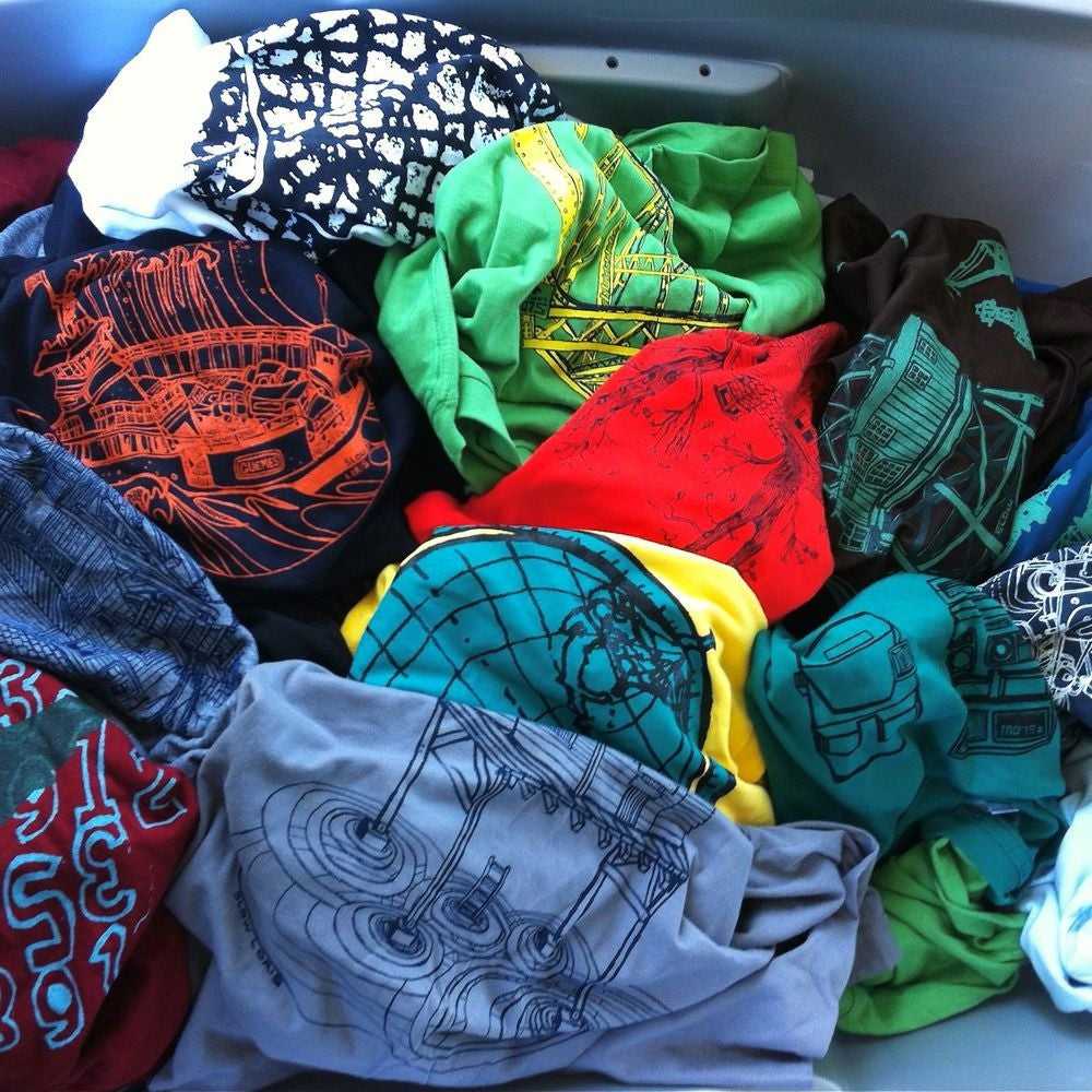pile of different colored t-shirts with different designs and colors of inks.