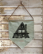 Green canvas wall art pennant printed with black A-Frame house.