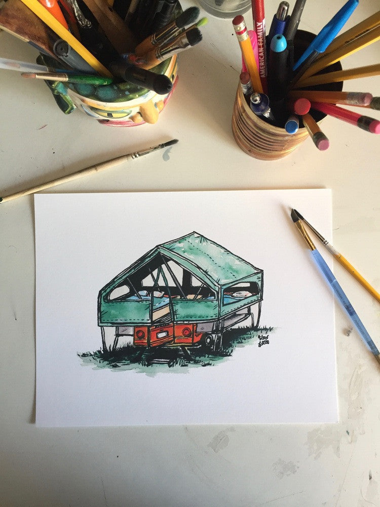 Painting of green and orange canvas tent camper trailer, laid on desk with pens and brushes.